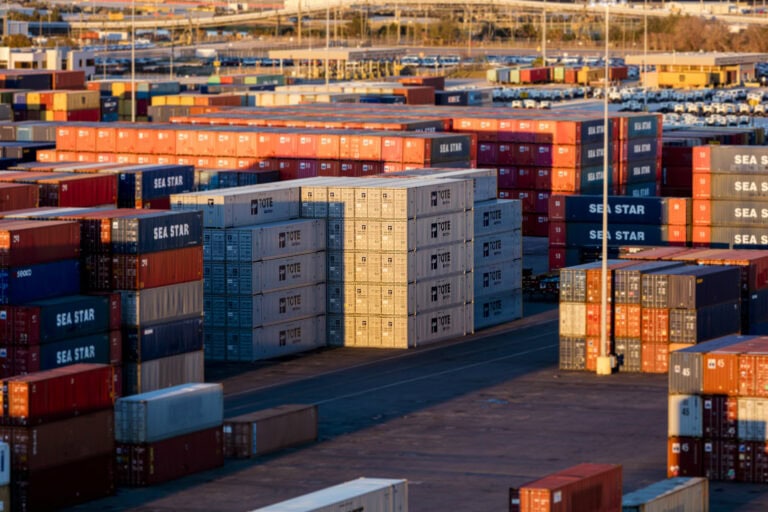 Container yard with stacked shipping containers in various colors under clear sky.