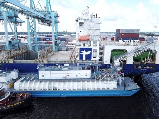 Refueling LNG Bunker Barge at port with cranes and containers in background.