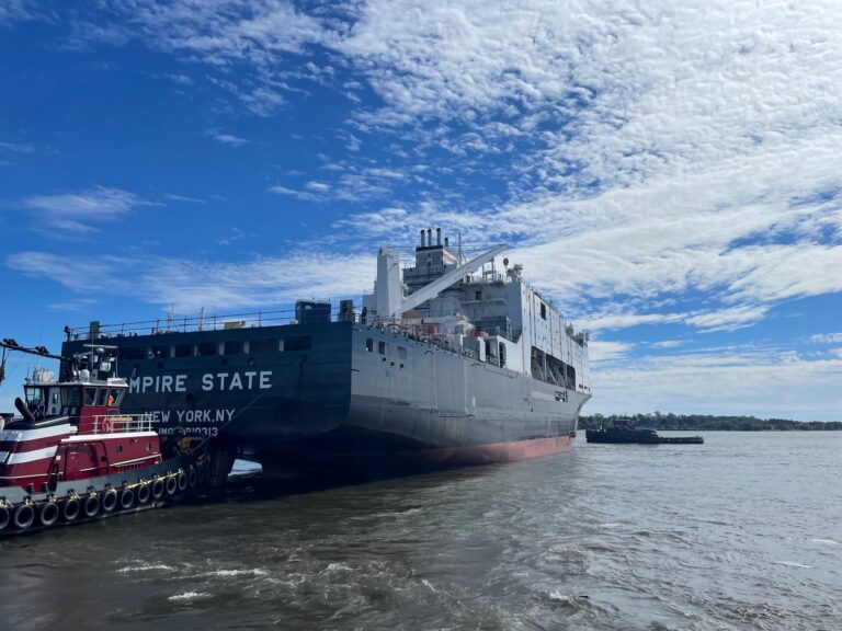The Empire State vessel docked at the port under a partly cloudy sky.
