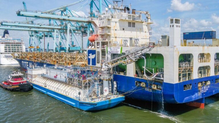 Large LNG-powered ship docked at port with cranes and other ships nearby.