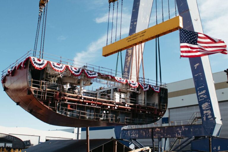Submarine being lifted by a large crane with American flag and patriotic decorations.