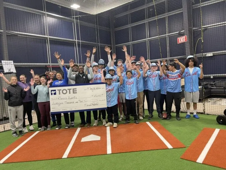 Group of people holding a large check inside a sports facility.