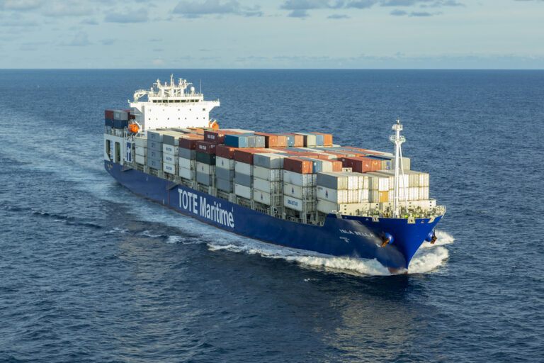 Container ship sailing on the ocean with containers on deck.