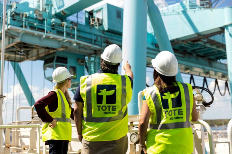 Workers in safety vests and helmets inspecting offshore platform.