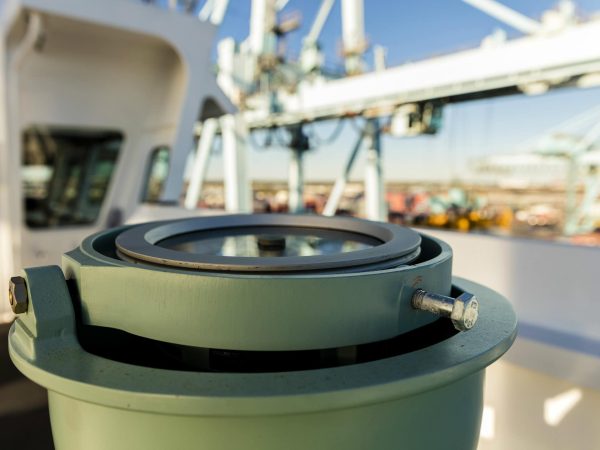 Close-up of a green marine compass on a boat deck.
