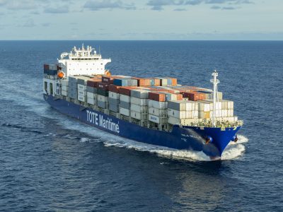 Container ship sailing on the ocean with containers on deck.